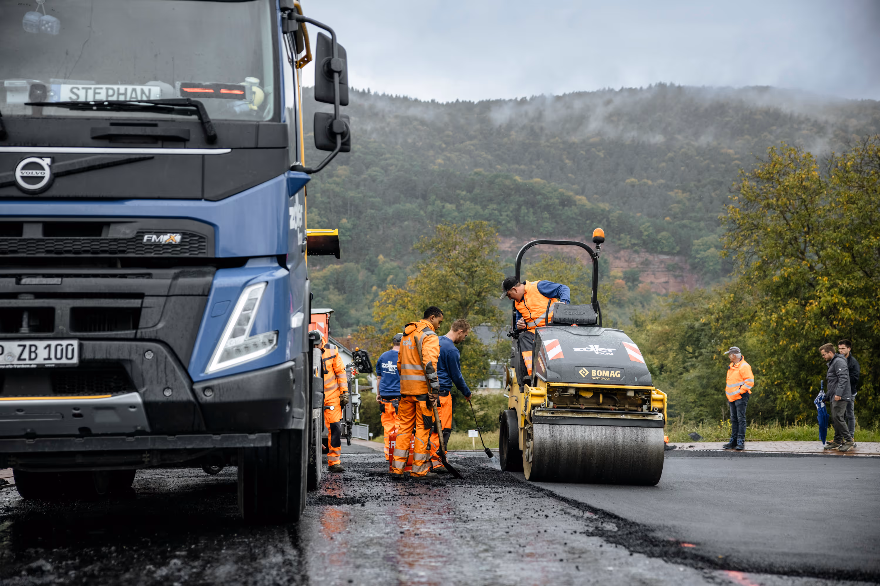 Straßenbauarbeiten der Zöller Bau GmbH mit LKW und Walze